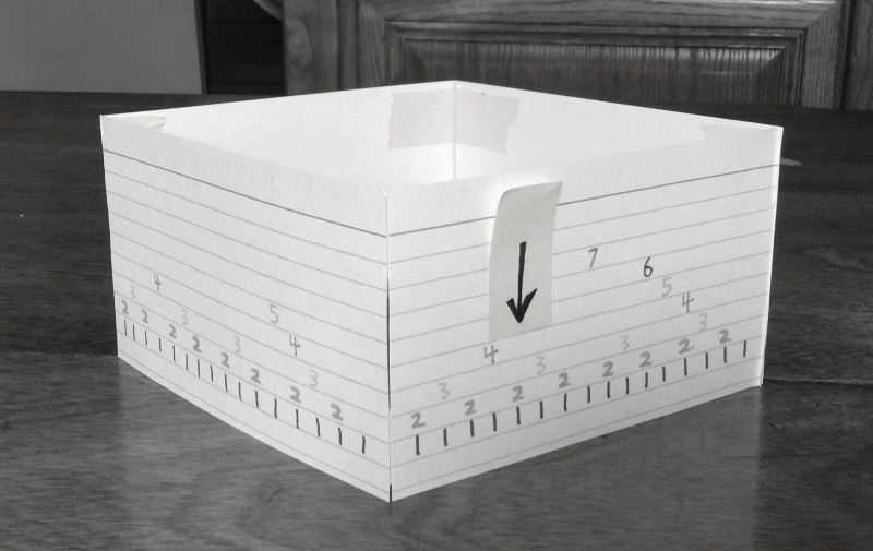 Four index cards standing on edge, taped together in a square. The numbers 1 through 7 appear on them in a regular pattern.